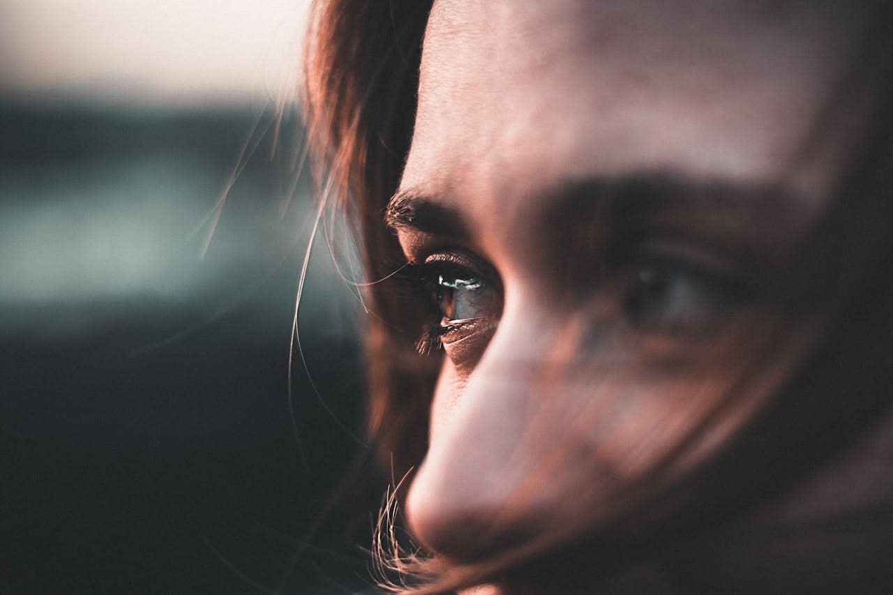 Close-up of a person’s face, focusing on their eyes and part of their nose, with strands of hair partially covering the face—evoking the introspective moments often explored during therapy sessions at Brooklyn Therapy.