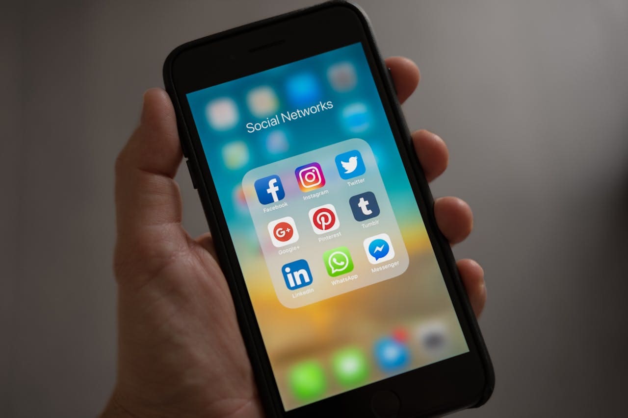 A hand holds a smartphone displaying a folder labeled “Social Networks” with various social media app icons on the screen, reflecting how Brooklyn Therapy and other therapist NYC services are adapting to digital trends in modern therapy.