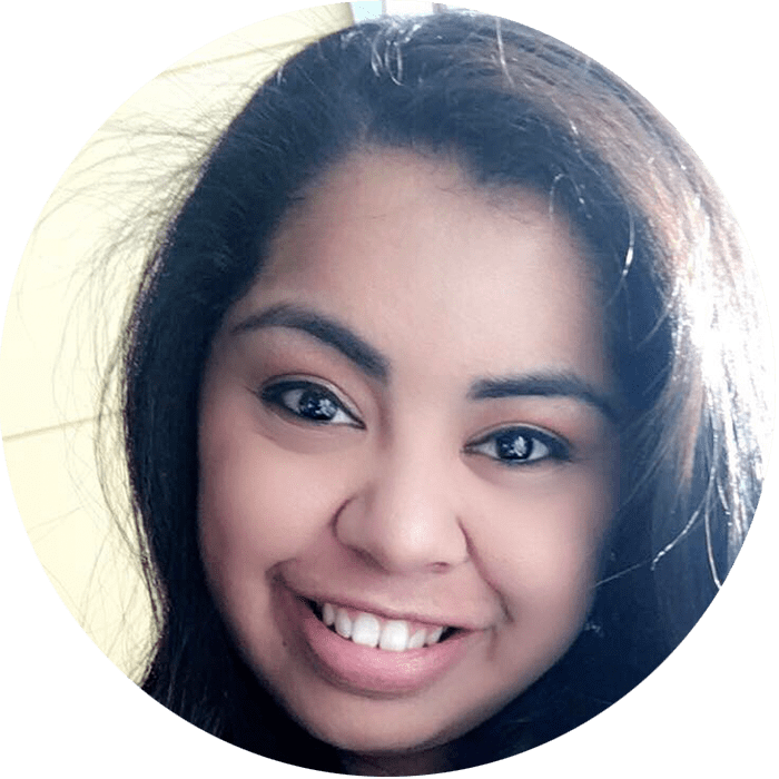 A person with long dark hair and dark eyes smiling at the camera, shown in close-up with a light background—capturing the approachable warmth you might find when starting therapy with a Brooklyn Therapy specialist or an experienced therapist NYC trusts.