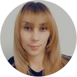 A person with straight, light brown hair and bangs is looking at the camera with a neutral expression against a plain background, evoking the calm and thoughtful atmosphere often found in Brooklyn Therapy sessions.