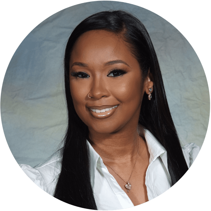 Smiling woman with long straight black hair, wearing a white shirt, necklace, earrings, and a nose ring, posed in front of a light-colored, textured background—an inviting image that reflects the welcoming atmosphere of Brooklyn Therapy for those seeking support from a compassionate therapist in NYC.