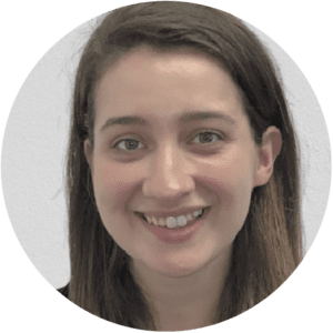 A woman with straight brown hair smiles at the camera. She is in front of a plain light-colored background, representing the welcoming atmosphere often found in Brooklyn Therapy sessions for those seeking a therapist in NYC.